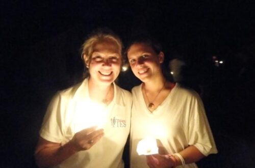 Mary Miles Loveless and her daughter Kate holding candles at the Camp Nakanawa Amazon Serenade in 2011, sharing a special moment illuminated by candlelight.