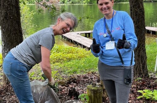 Cleaning up along Lake Aloaloa’s shoreline with docks and calm water in the background.