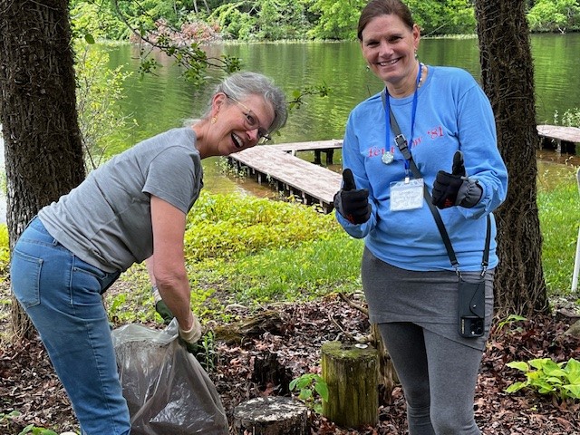 Cleaning up along Lake Aloaloa’s shoreline with docks and calm water in the background.